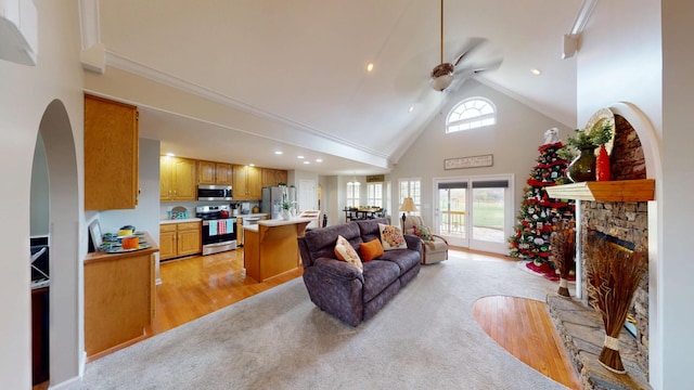 living area featuring a stone fireplace, plenty of natural light, high vaulted ceiling, and ceiling fan