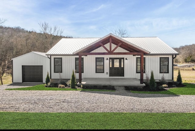 modern inspired farmhouse featuring a garage, driveway, a porch, board and batten siding, and metal roof