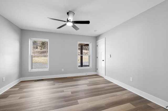 spare room featuring baseboards, a healthy amount of sunlight, and wood finished floors