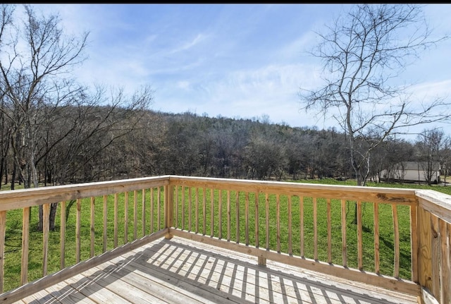 wooden terrace with a forest view and a lawn