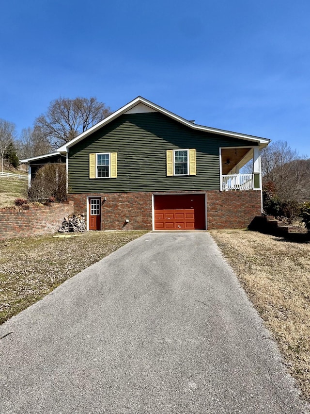 view of side of home with a garage, brick siding, and aphalt driveway