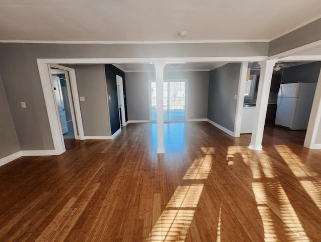 empty room featuring baseboards, dark wood-type flooring, and ornate columns