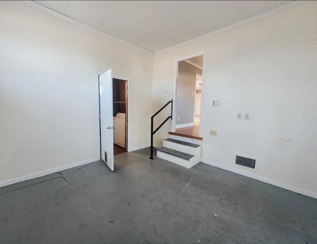 spare room featuring visible vents, concrete flooring, baseboards, and ornamental molding