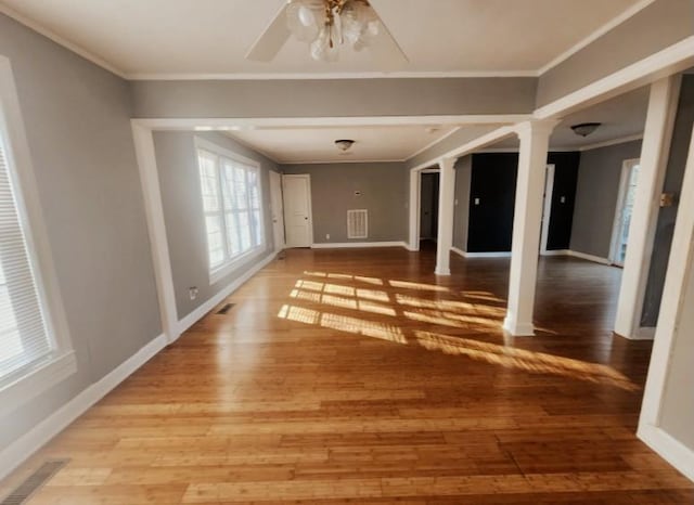 interior space featuring light wood-type flooring, visible vents, ornamental molding, and ornate columns