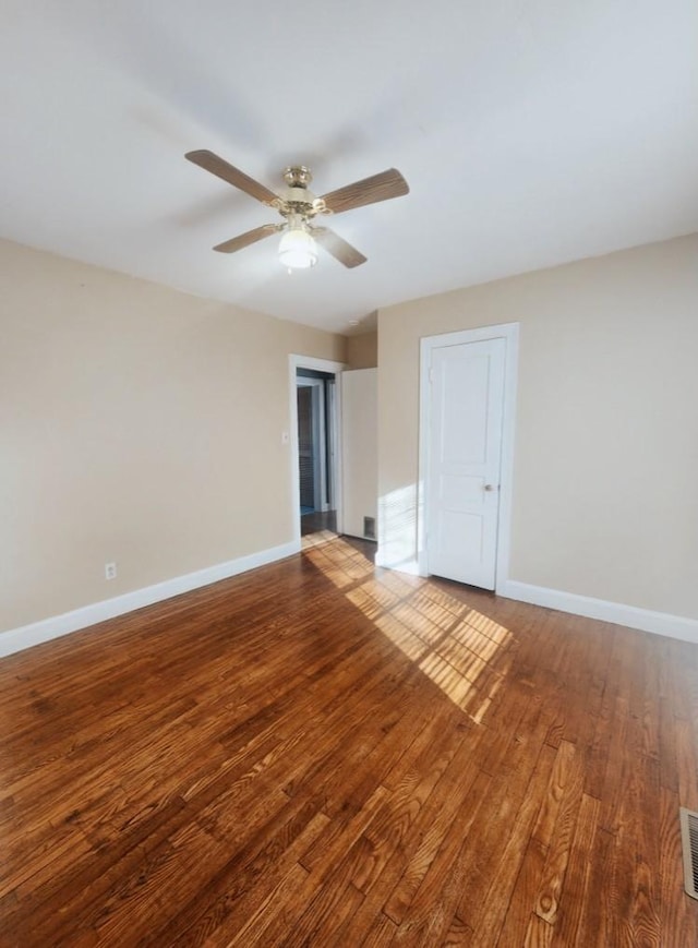 empty room with visible vents, wood finished floors, baseboards, and ceiling fan