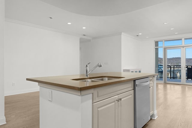 kitchen with an island with sink, a sink, stainless steel dishwasher, crown molding, and light wood-type flooring