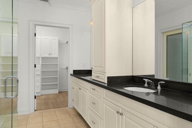 full bath with tile patterned flooring, crown molding, double vanity, a stall shower, and a sink