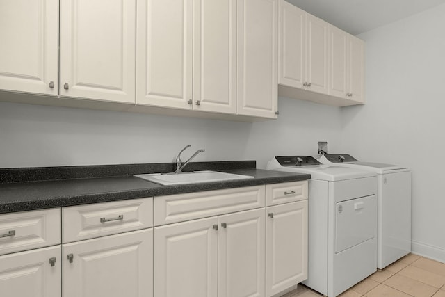 washroom featuring baseboards, washer and clothes dryer, light tile patterned floors, cabinet space, and a sink