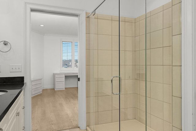 full bathroom featuring vanity, wood finished floors, baseboards, a stall shower, and ornamental molding