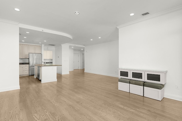 unfurnished living room with visible vents, recessed lighting, light wood-style floors, and ornamental molding