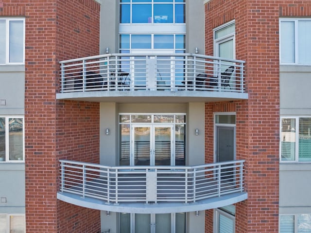 property entrance with brick siding and a balcony