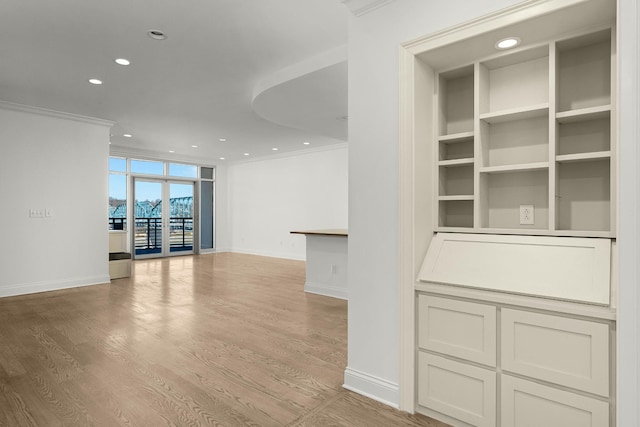 unfurnished living room featuring light wood-type flooring, built in shelves, ornamental molding, recessed lighting, and baseboards