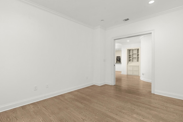 spare room featuring visible vents, light wood-style floors, baseboards, and ornamental molding