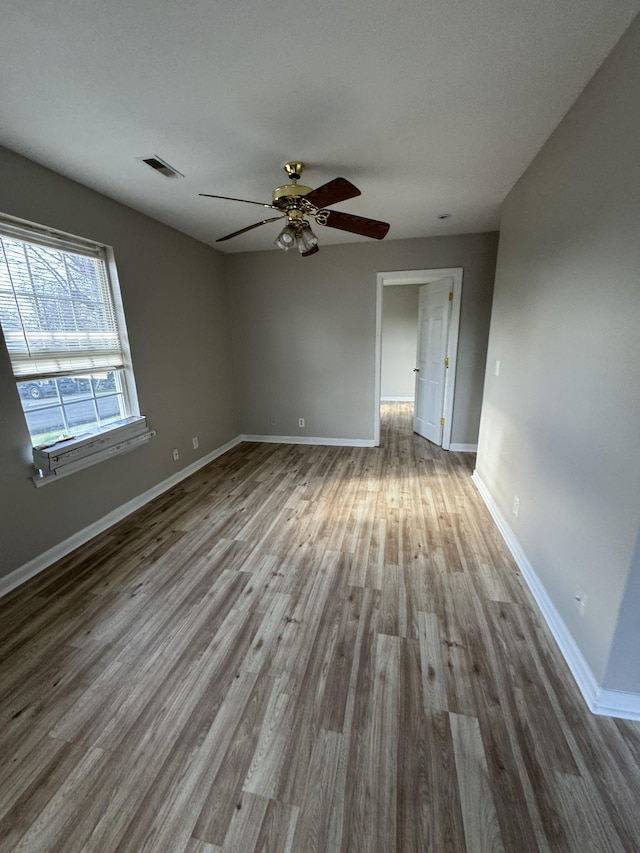 spare room featuring visible vents, baseboards, and wood finished floors