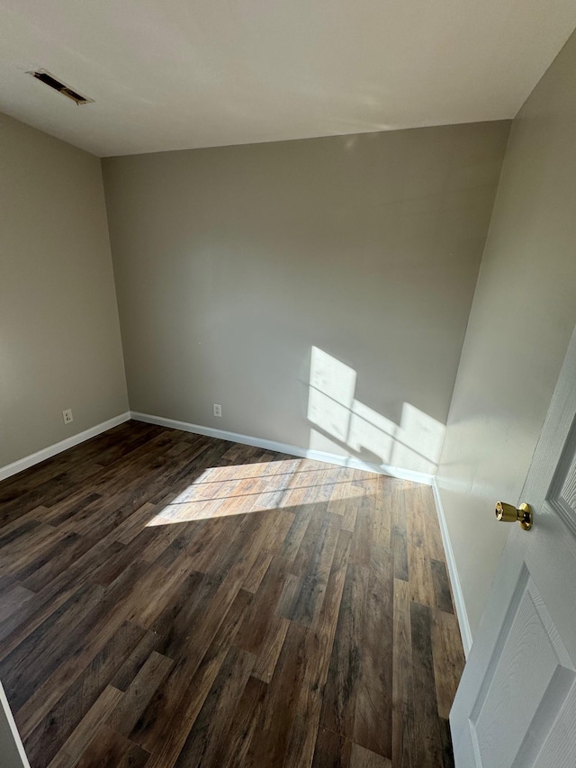 spare room featuring visible vents, baseboards, and dark wood-style flooring