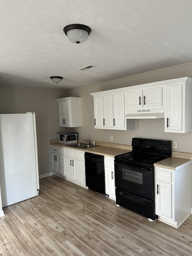 kitchen with a sink, black appliances, white cabinets, under cabinet range hood, and light wood-type flooring