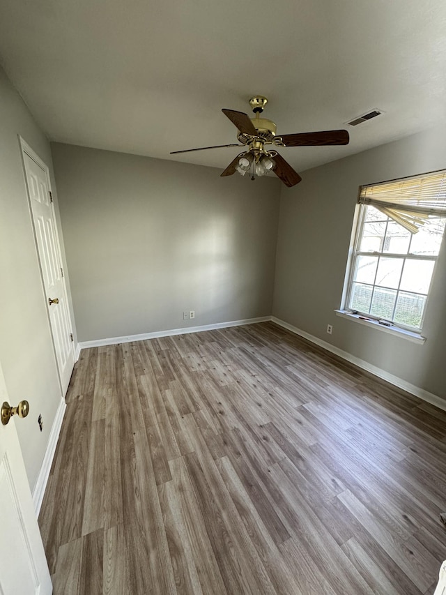 spare room featuring visible vents, baseboards, and wood finished floors