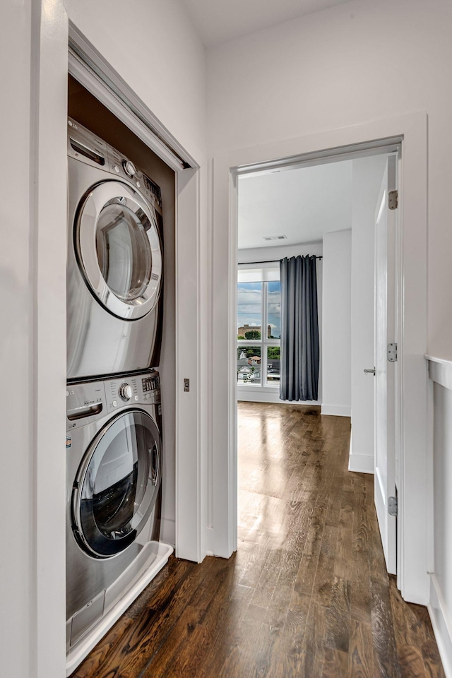 washroom with laundry area, wood finished floors, baseboards, and stacked washing maching and dryer