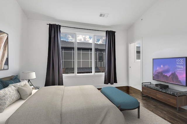 bedroom with lofted ceiling, wood finished floors, visible vents, and baseboards