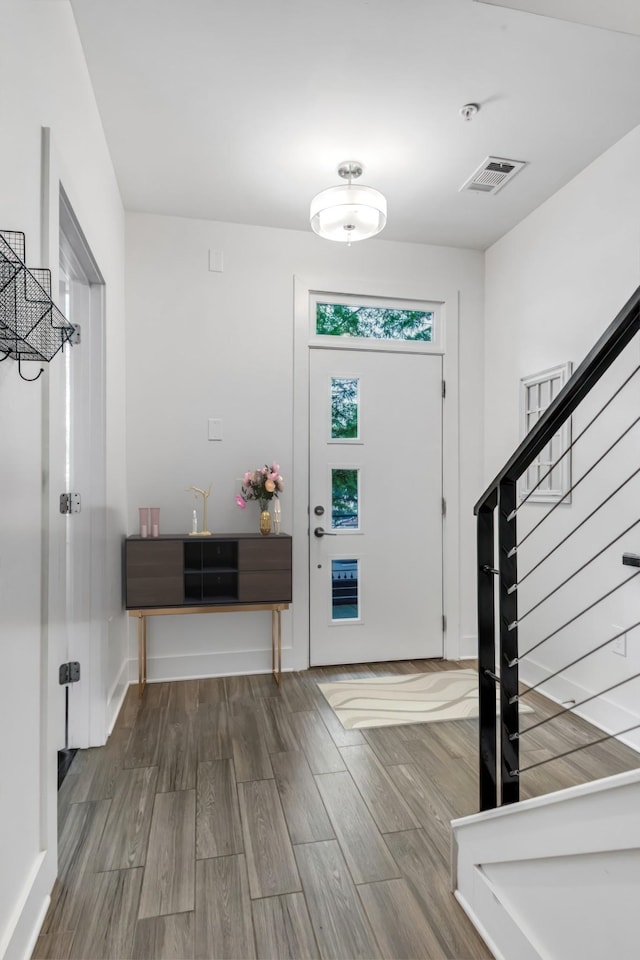 foyer with stairway, wood finished floors, visible vents, and baseboards