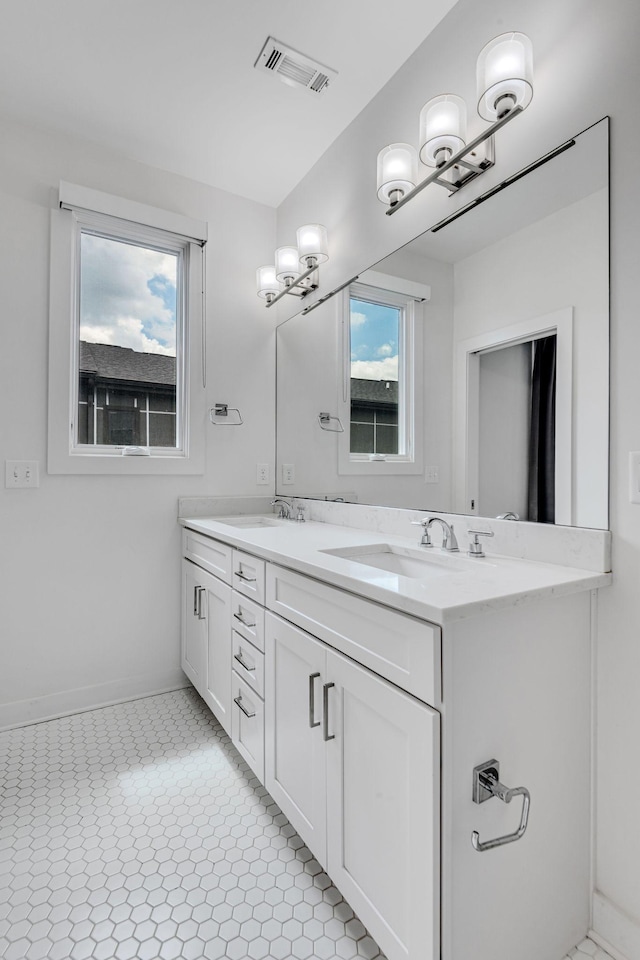 full bathroom featuring double vanity, visible vents, baseboards, and a sink