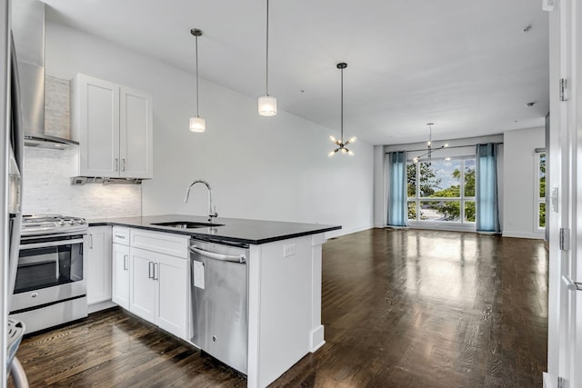 kitchen featuring dark countertops, wall chimney range hood, a peninsula, stainless steel appliances, and a sink