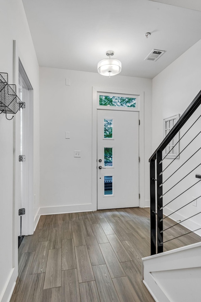 entryway featuring visible vents, stairs, baseboards, and wood finished floors