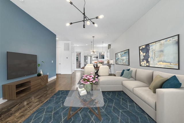 living room featuring dark wood-style floors, visible vents, baseboards, and an inviting chandelier