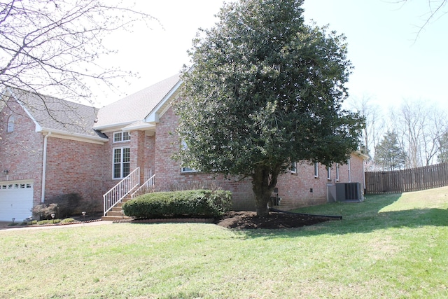 view of side of property featuring central AC unit, a yard, fence, and brick siding