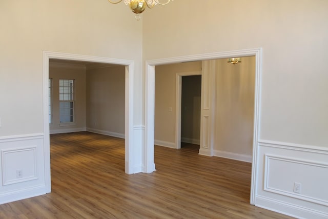 spare room with a decorative wall, light wood-style floors, a wainscoted wall, and a chandelier