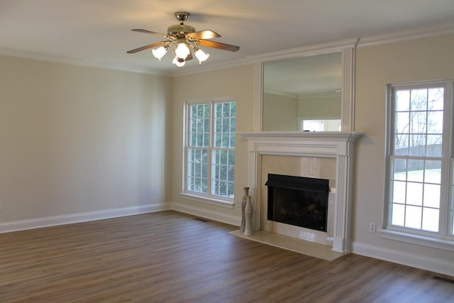 unfurnished living room featuring a tiled fireplace, a healthy amount of sunlight, crown molding, and wood finished floors