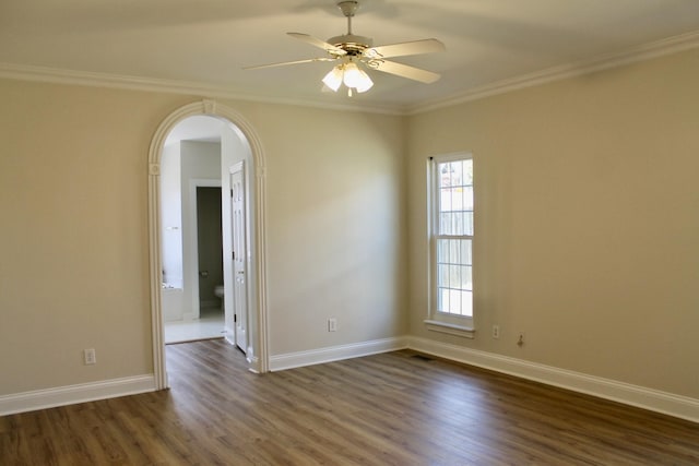 spare room featuring dark wood-type flooring, a ceiling fan, baseboards, and ornamental molding