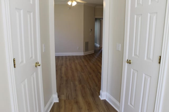 hallway featuring visible vents, dark wood-type flooring, baseboards, and ornamental molding