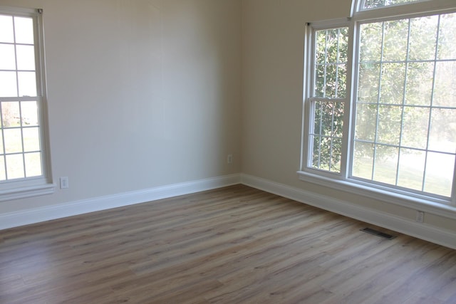 unfurnished room with visible vents, baseboards, and wood finished floors