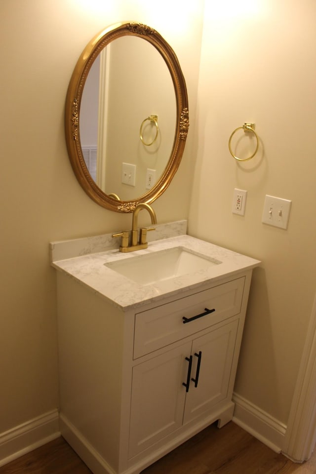 bathroom featuring vanity, wood finished floors, and baseboards