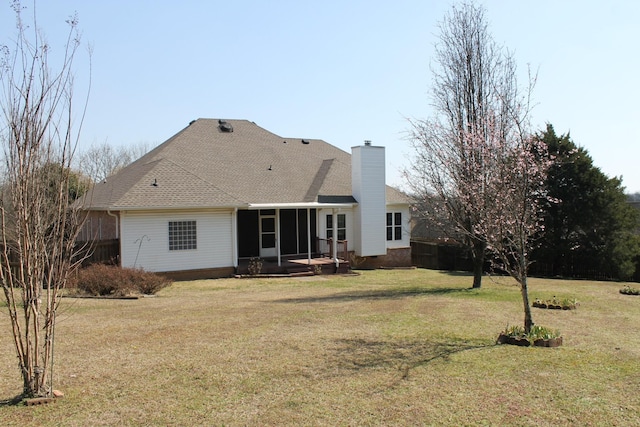 back of property featuring roof with shingles, a lawn, a sunroom, and a chimney