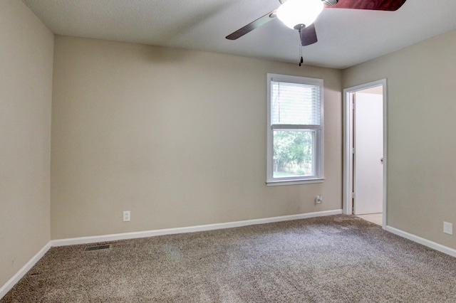 carpeted spare room featuring a ceiling fan and baseboards