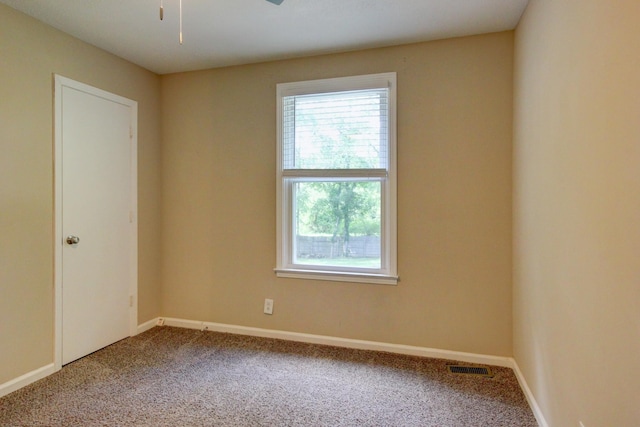 carpeted empty room with visible vents, baseboards, and a ceiling fan