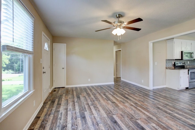 unfurnished living room featuring ceiling fan, baseboards, and dark wood-style flooring