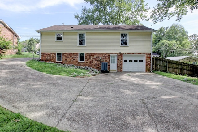 view of property exterior with an attached garage, fence, brick siding, and driveway