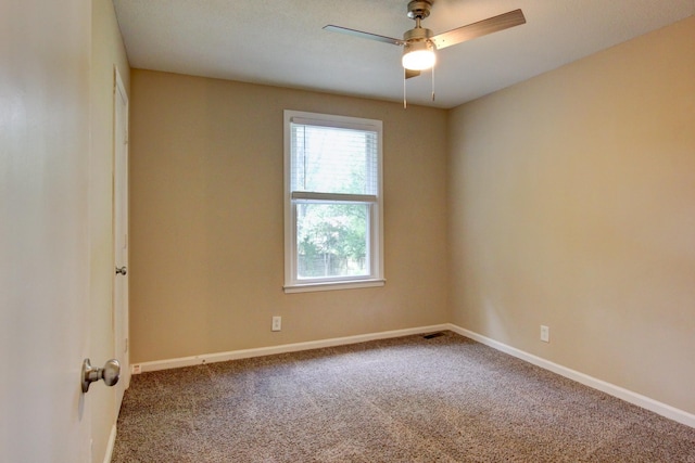 carpeted spare room with visible vents, baseboards, and a ceiling fan