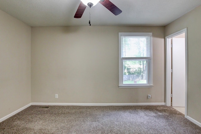 carpeted empty room with visible vents, baseboards, a textured ceiling, and ceiling fan