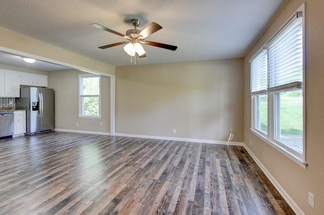 unfurnished living room with dark wood finished floors, baseboards, and a wealth of natural light