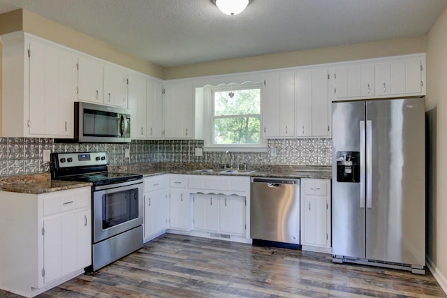 kitchen featuring dark wood-style flooring, a sink, white cabinets, appliances with stainless steel finishes, and backsplash