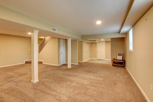 basement featuring visible vents, baseboards, stairs, carpet flooring, and a textured ceiling