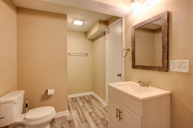 bathroom with vanity, wood finished floors, visible vents, baseboards, and toilet