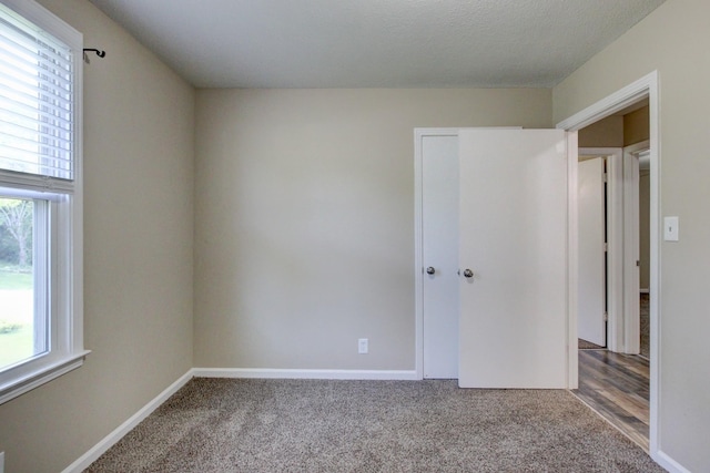 unfurnished bedroom with a textured ceiling, baseboards, and carpet floors