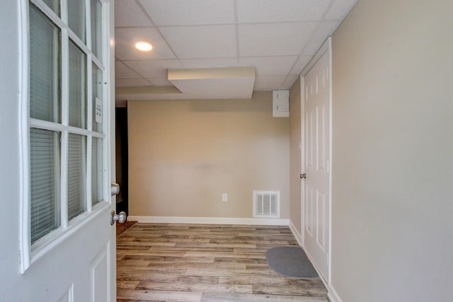 unfurnished room with visible vents, a drop ceiling, baseboards, and wood finished floors