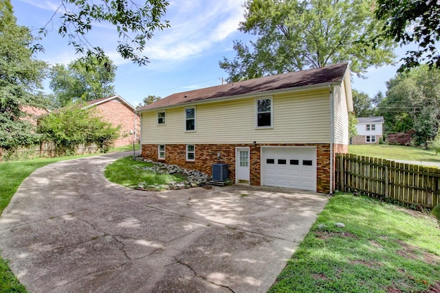 exterior space with fence, a yard, concrete driveway, a garage, and brick siding