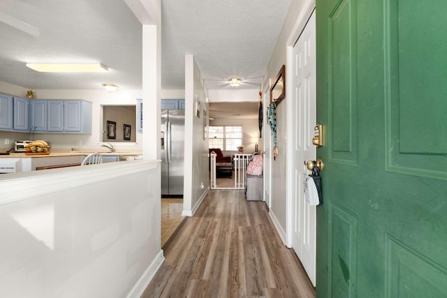 foyer entrance featuring light wood-style flooring, baseboards, and a textured ceiling